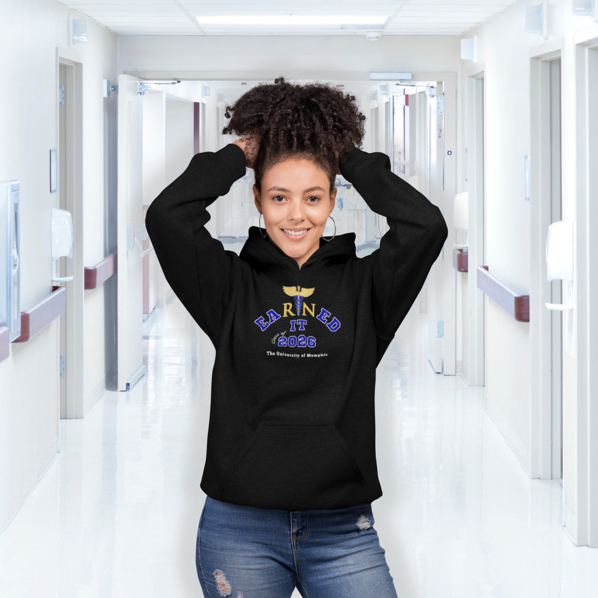 Person wearing a nurse black hoodie with text in a hospital hallway